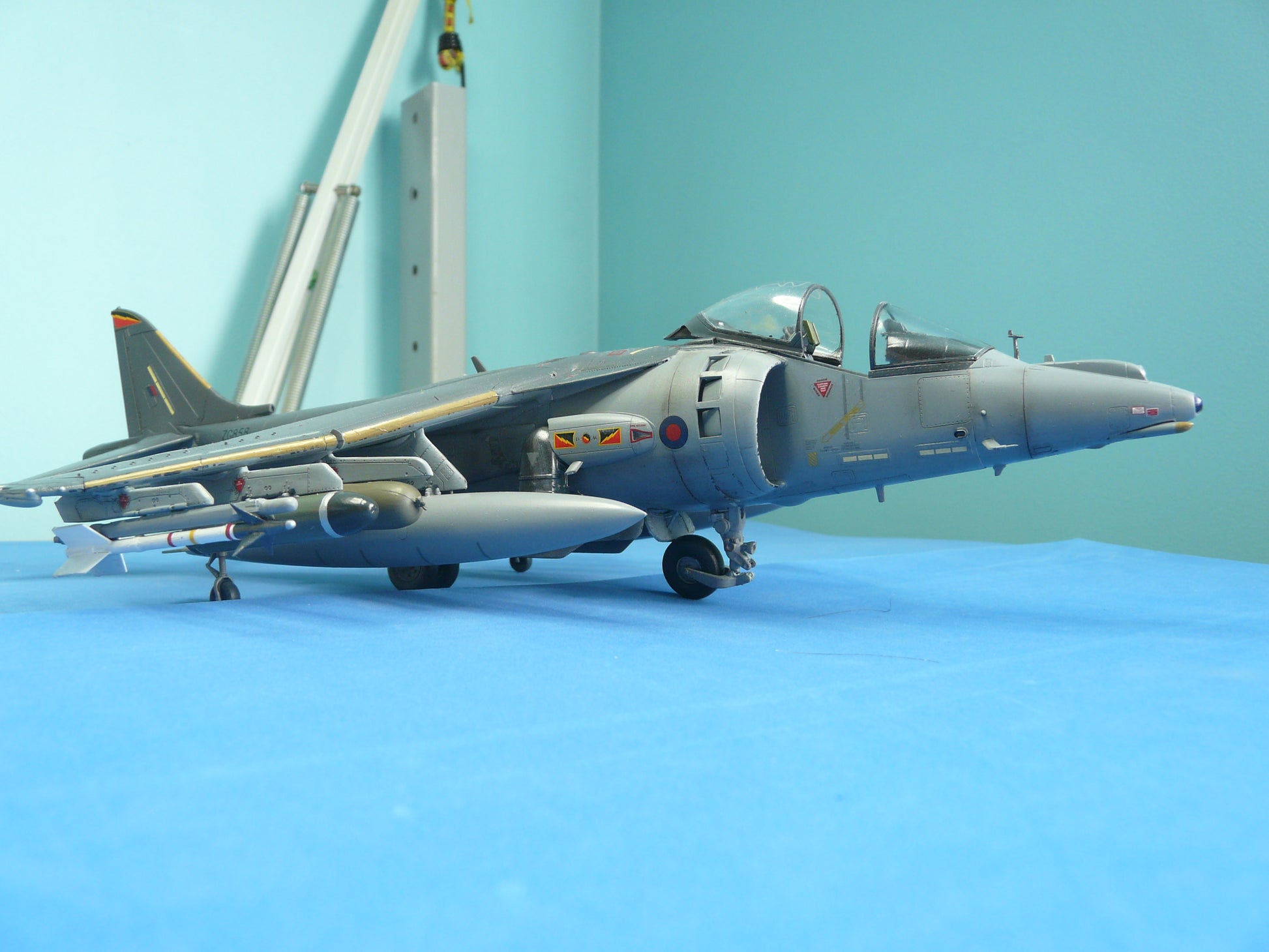 Model of a fighter jet on a blue surface with a light blue background